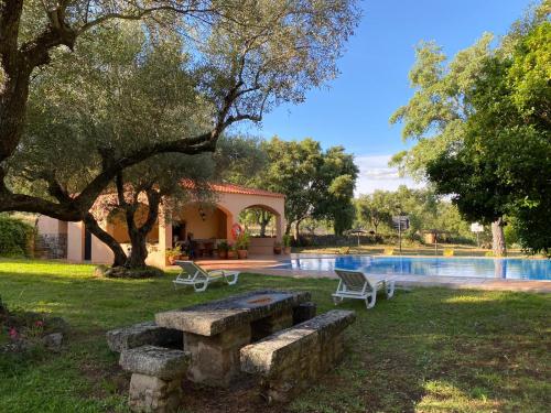 un parque con bancos y una piscina en Apartamentos Rurales La Macera ****, en Valencia de Alcántara