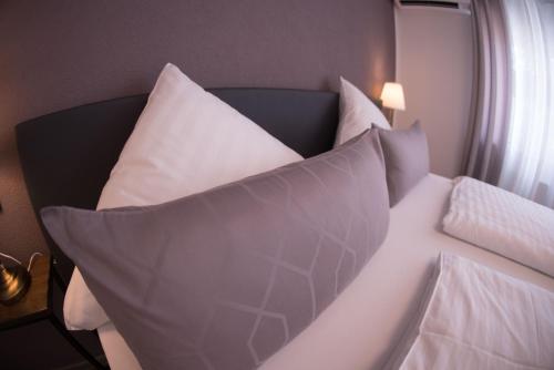 a bed with white pillows on it in a room at CityApartment K1 KLIMATISIERT in Friedrichshafen