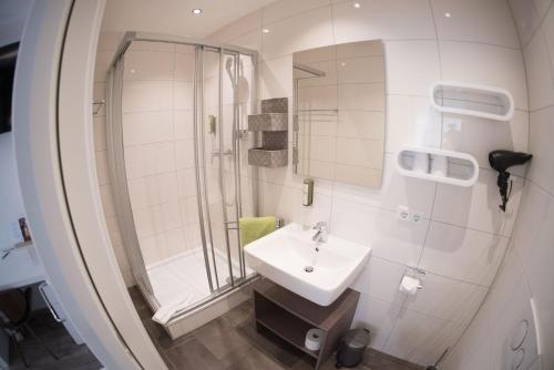a white bathroom with a sink and a shower at CityApartment K1 KLIMATISIERT in Friedrichshafen