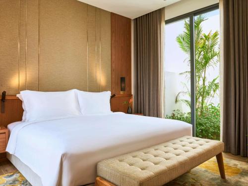 a bedroom with a large bed and a large window at Mövenpick Villas & Residences Phu Quoc in Phu Quoc