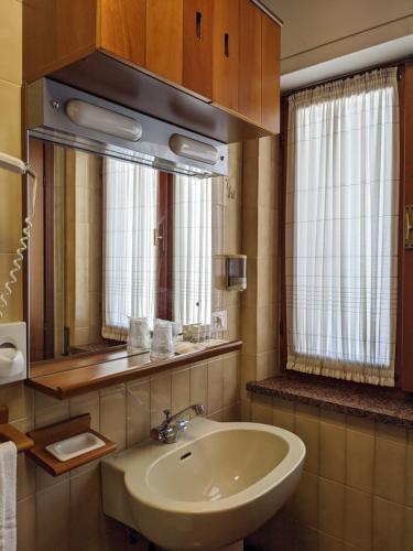 y baño con lavabo y espejo. en Hotel Corallo, en Lignano Sabbiadoro