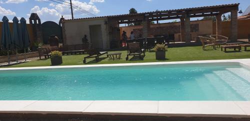 una piscina en un patio con sillas y mesas en Casa Rural La Piedra De Juana en Malpartida de Cáceres