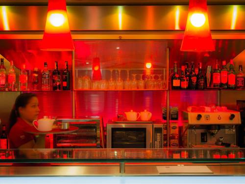 a woman sitting at a counter in a restaurant at ibis Porto Centro São Bento in Porto