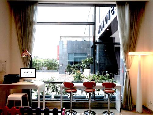 a room with a large window with red chairs and a table at Novotel Chennai OMR in Chennai