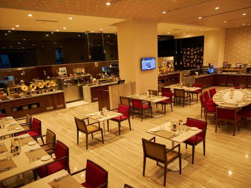 a restaurant with tables and chairs and a bar at Novotel Chennai OMR in Chennai