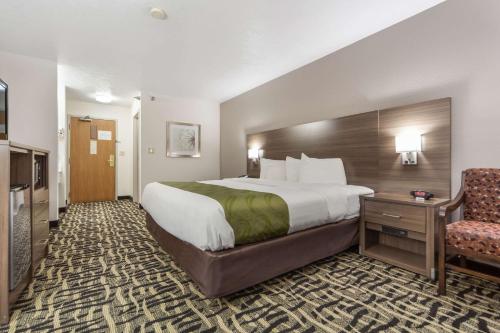 a hotel room with a large bed and a chair at Quality Inn & Suites Omaha Chalco in Omaha