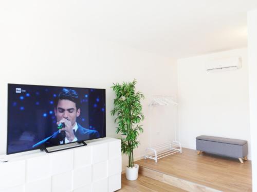 uma televisão de ecrã plano numa parede branca numa sala de estar em Guest House - La bella vita em Orosei