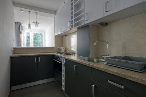 a kitchen with black cabinets and a sink at aleja 3 maja 7B by Homeprime in Warsaw