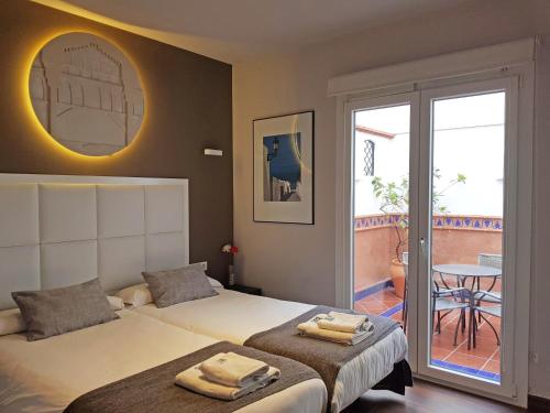 1 Schlafzimmer mit 2 Betten und einem Balkon mit einem Tisch in der Unterkunft Apartamentos Caballerizas Granada con parking gratuito en pleno centro in Granada