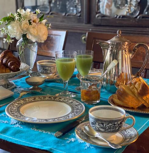 - une table avec des assiettes, des verres de jus de fruits et des pâtisseries dans l'établissement Manoir de Ghaisne, à Freigné