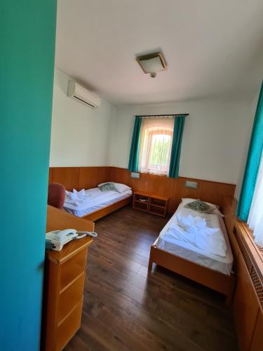 a room with two beds and a window at István Parkhotel és Gasztrofarm in Sormás