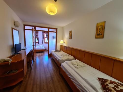 a room with two beds and a desk and a television at István Parkhotel és Gasztrofarm in Sormás