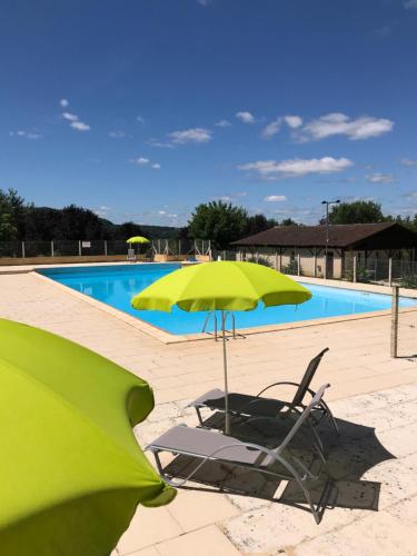 a green umbrella and a chair next to a swimming pool at Camping Le Mondou in Saint-Julien-de-Lampon