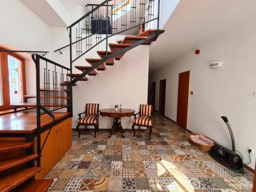 a room with a table and a spiral staircase at István Parkhotel és Gasztrofarm in Sormás