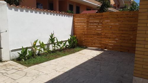 a wooden fence next to a white wall at un passo dal mare in Fiumicino
