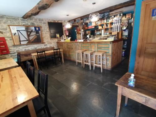 - un bar dans un restaurant avec des tables et des chaises en bois dans l'établissement El Puente Peregrino, à Trabadelo