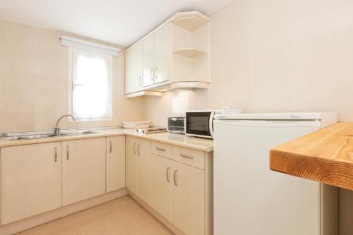 a kitchen with white cabinets and a white refrigerator at Apartamentos Los Arcos in Santa Eularia des Riu
