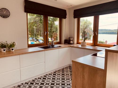 a kitchen with white cabinets and a clock on the wall at Villa Toscana in Gietrzwałd