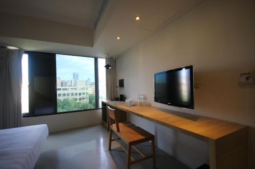 a room with a desk with a television and a window at Hotel Papa Whale-Kaohsiung Formosa Boulevard in Kaohsiung