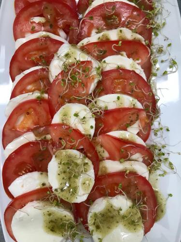 a plate of tomatoes with cheese and herbs at Restauracja Sonata in Zwierzyniec