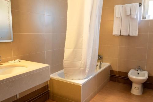 a bathroom with a tub and a sink and a toilet at Hotel Santa Cecília in Fátima