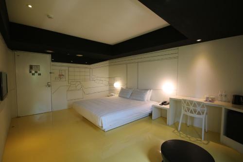 a bedroom with a bed and a desk with a chair at Hotel Papa Whale-Kaohsiung Formosa Boulevard in Kaohsiung