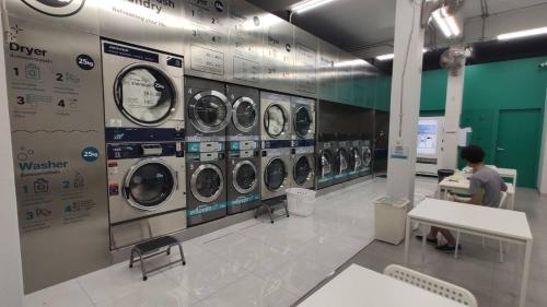 a man sitting in front of a row of washing machines at Nap at 265 Donmeaung in Bangkok