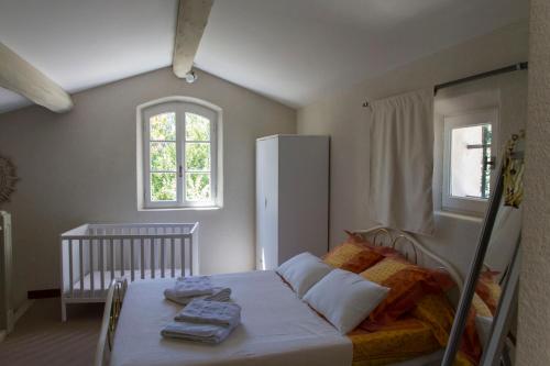 a bedroom with a bed with a crib and two windows at Maison de campagne au charme provençal in Saint-Rémy-de-Provence