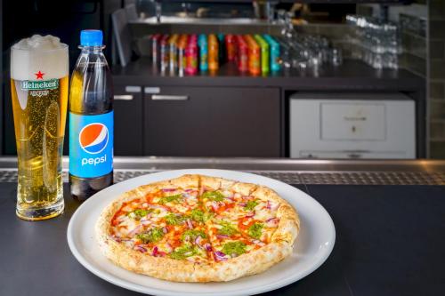 a pizza on a plate next to a bottle of beer at a&o Budapest City in Budapest