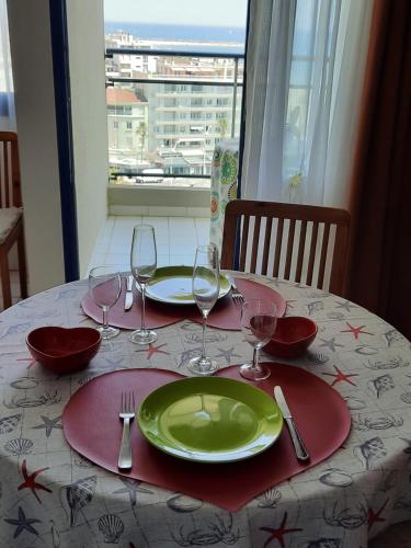 - une table avec une assiette verte et des verres à vin dans l'établissement Studio Sympa, à Canet