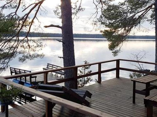 a wooden deck with a tree on a lake at Holiday Home Lähesniemi by Interhome in Hokkanen