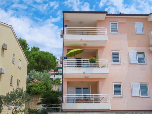 a pink building with a balcony with a green umbrella at Apartment Egle by Interhome in Rabac