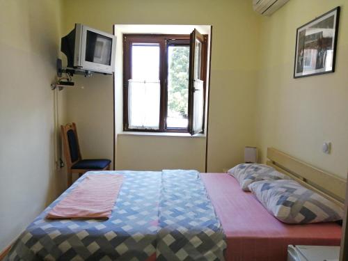 a bedroom with a bed and a television at Hotel Pelikan in Virpazar