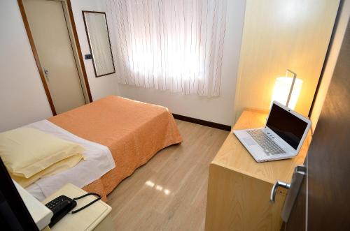 メストレにあるオテル サン ジュリアーノのベッド1台、ノートパソコン1台、デスクが備わる客室です。
