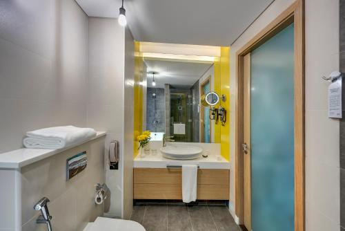 a bathroom with a sink and a toilet and a mirror at URBAN Al Khoory Hotel in Dubai