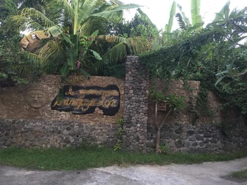 a stone wall with a sign on it at Pranajaya loka villa in Tejakula