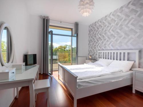 1 dormitorio con cama blanca, escritorio y ventana en VacationClub – Diune Apartament 60, en Kołobrzeg