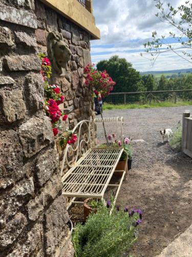 a white bench sitting next to a stone wall with flowers at Lavender cottage in Gloucester