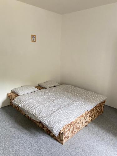 a bed in a room with a white wall at Penzion Hřensko in Hřensko