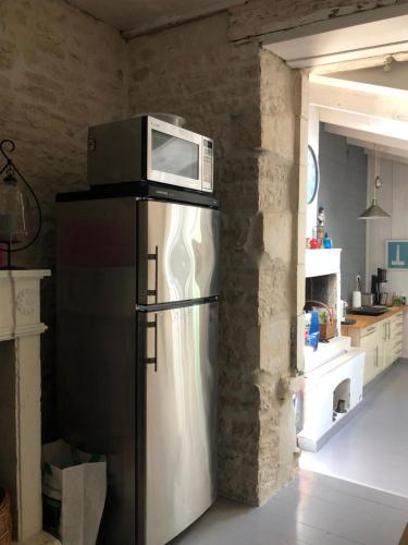 a microwave on top of a refrigerator in a kitchen at L'Olivier de Milou in Le Bois-Plage-en-Ré