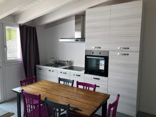 kuchnia z drewnianym stołem z fioletowymi krzesłami w obiekcie Corte del Garda Home w mieście Castelnuovo del Garda