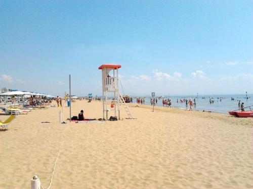 a lifeguard tower on a beach with people in the water at Cristallo Sea View in Lignano Sabbiadoro