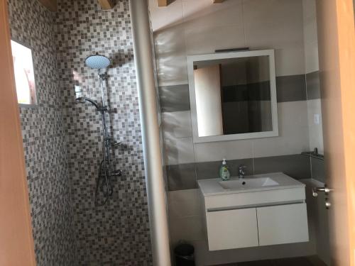 a bathroom with a sink and a shower with a mirror at Casas da Moagem in São Domingos