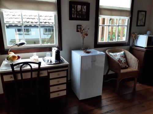 eine Küche mit einem Kühlschrank, einem Tisch und 2 Fenstern in der Unterkunft Casa do Sr. Falcão in Miranda do Corvo