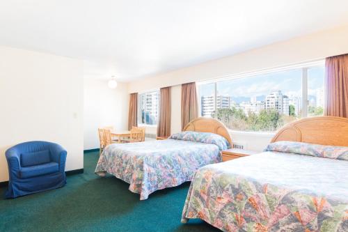 a hotel room with two beds and a window at English Bay Hotel in Vancouver