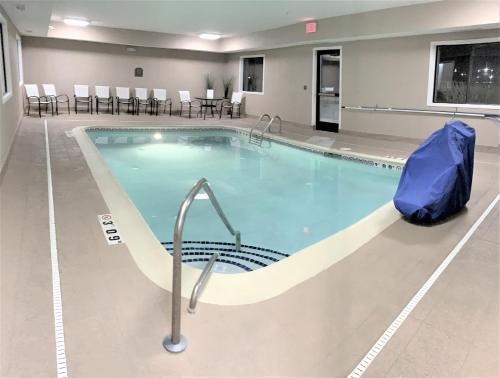 una gran piscina en una sala de hospital con sillas y mesas en Baymont by Wyndham Paw Paw, en Paw Paw