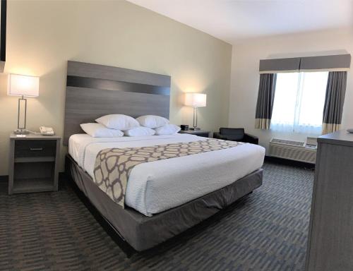a hotel room with a large bed and two windows at Baymont by Wyndham Paw Paw in Paw Paw