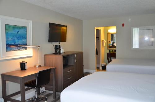 a hotel room with a bed and a desk and a bed at Opal Hotel & Suites in Orlando