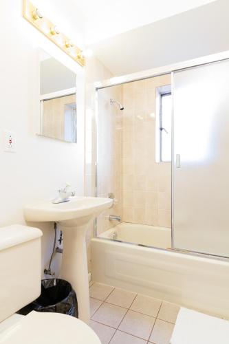 a white bathroom with a sink and a shower at English Bay Hotel in Vancouver