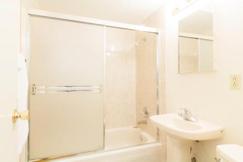 baño blanco con ducha y lavamanos en English Bay Hotel, en Vancouver